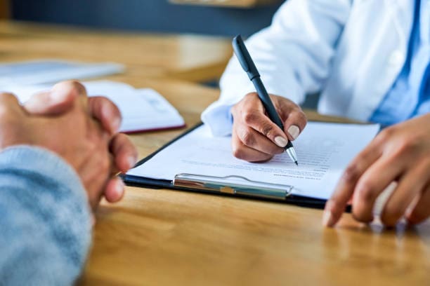 Closeup shot of a doctor writing notes during a consultation with a patient Closeup shot of a doctor writing notes during a consultation with a patient