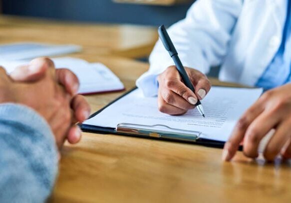 Closeup shot of a doctor writing notes during a consultation with a patient Closeup shot of a doctor writing notes during a consultation with a patient